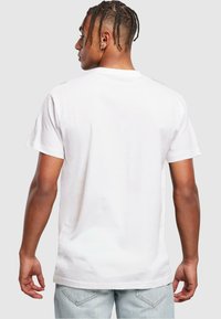 White cotton t-shirt with short sleeves, crew neck, and a relaxed fit. Smooth texture and no visible graphics or patterns.
