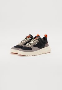Baskets au design en matériaux mixtes avec du daim gris et noir, une semelle intermédiaire blanche douce et des accents oranges à l'arrière et sur la languette.