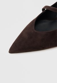 Καφέ καστόρινο παπούτσι με μυτερή μύτη, σχέδιο με ανοίγματα και λεπτό λουράκι πάνω από τον πάτο, με λείο μαύρο εσωτερικό.