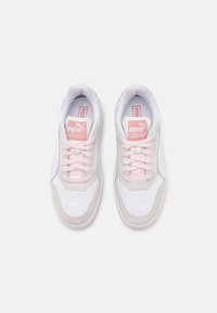 Baskets blanches avec des accents roses, présentant une boîte à orteils en daim texturé, des détails perforés et un laçage classique. Logo Puma sur la languette.