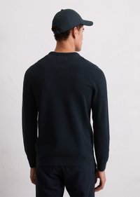 Pulover tricotat de culoare bleumarin cu un design texturat, guler rotund și mâneci lungi. Purtați cu o șapcă de baseball asortată, de culoare bleumarin.