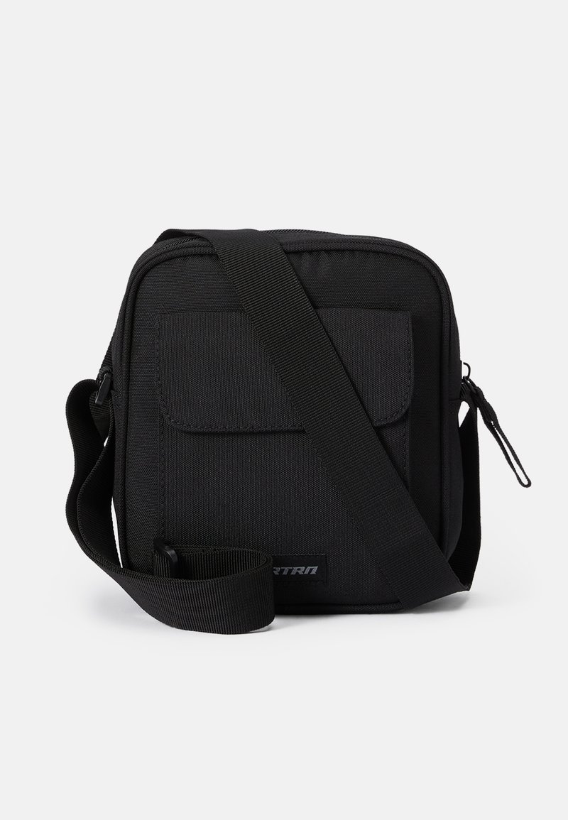Čierna crossbody taška vyrobená z odolnej textílie, s predným vreckom, zipsovým uzáverom, nastaviteľným popruhom a obdlžníkovým tvarom.