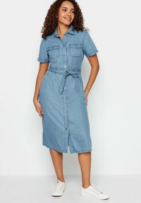 Denim takki mekko vaaleansinisenä, lyhyillä hihoilla, kauluksella, kahdella rintataskulla, nappikiinnityksellä edessä ja vyötäröllä vyöllä.