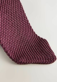 Cravate en textile tissé de couleur violet profond, avec une surface texturée et côtelée, et une extrémité pointue. Le design est simple et discret, adapté à une tenue formelle.