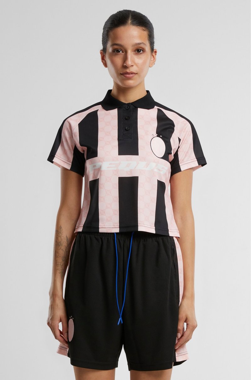 Roza in črna skrajšana polo majica s kratkimi rokavi ima navpične črte, ovratnik z gumbi in logo. Črni kratki hlače z modrim vrvico.