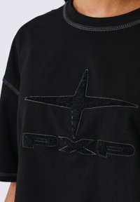 T-shirt nera con logo testurizzato nero e design a stella. Cuciture a contrasto attorno al collo e alle maniche. Tessuto morbido e liscio.