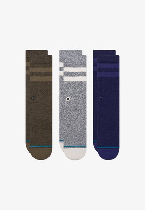 Tre paia di calzini: marrone scuro a righe, grigio con righe bianche e blu, tutti caratterizzati da una texture morbida e accenti colorati.