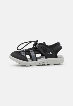 Sandalias negras con correas grises y cordones ajustables. Tienen un upper texturizado y una suela de goma blanca con un patrón de banda de rodadura resistente.