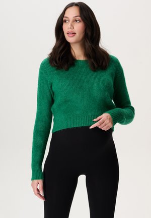 Groene gebreide trui met een geribbelde textuur, een cropped ontwerp en lange mouwen, gecombineerd met zwarte high-waisted legging.