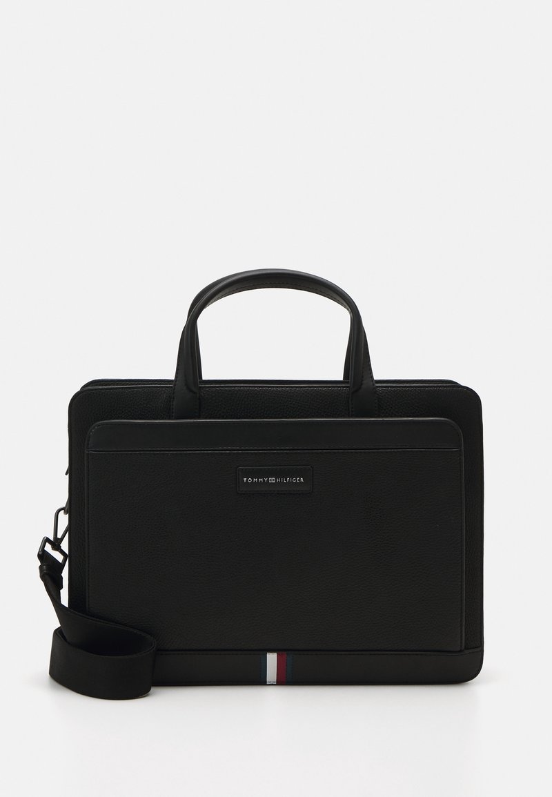 Sac pour ordinateur portable en cuir noir avec deux poignées supérieures, sangle réglable et détail de rayure horizontale en rouge, blanc et bleu en bas.