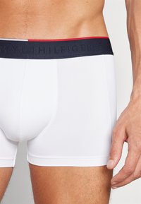 Caleçons boxers blancs avec une taille de couleur marine accentuée de rouge et un logo en relief. Tissu lisse avec une coupe ajustée.