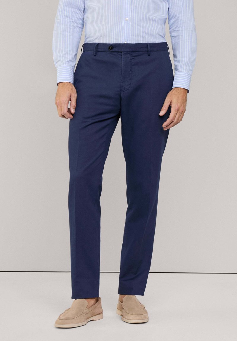 Marineblaue Hosen aus einem glatten Stoff, mit einem geraden Bein-Design, Taschen vorne und einem Knopfverschluss an der Taille.