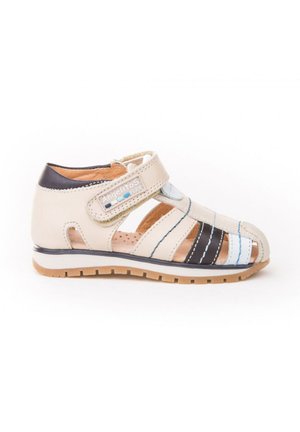 Sandalia para niño pequeño de cuero beige y negro con tira de velcro etiquetada "Angelitos", diseño de punta abierta y suela de goma marrón.