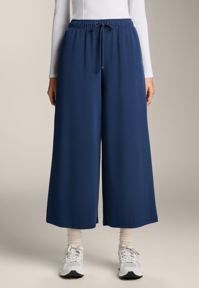 Mornarsko modre hlače širokega kroja z elastiko v pasu in nastavljivim vrvico. Narejene iz mehke tkanine, s sproščenim krojem.