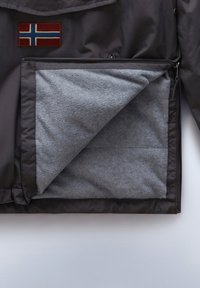 Dunkelgraue Jacke mit teilweise geöffnetem Frontreißverschluss, die ein weiches hellgraues Fleecefutter und ein aufgenähtes norwegisches Flaggenemblem auf der Brust zeigt.