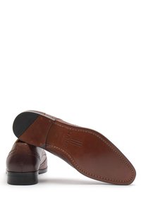 Scarpe da cerimonia in pelle marrone con dettagli a brogue, finitura liscia e suola in gomma nera a contrasto. La soletta interna è personalizzata con il marchio.