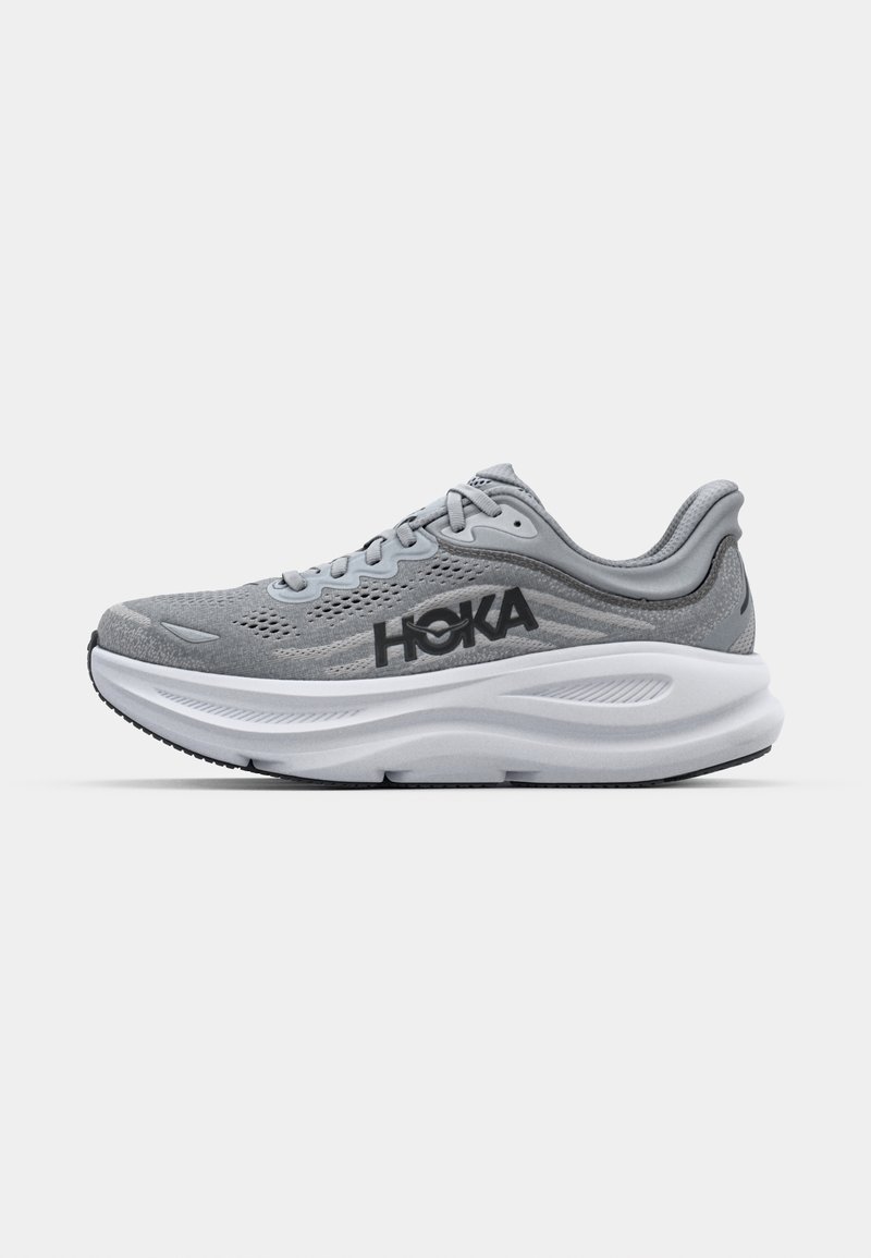 Gray athletic shoe with mesh upper, HOKA branding, cushioned midsole, and rubber outsole. Features curved design and textured details.