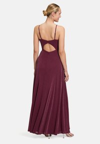 Robe de soirée bourgogne avec bretelles spaghetti, corsage ajusté, dos ouvert et jupe fluide. Le tissu a un léger éclat.