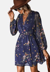 Navyblauwe bloemenjurk met lange, doorzichtige pofmouwen, een V-hals en een elastische taille. Heeft kleurrijke bloempatronen overal.