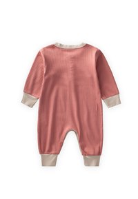 Rievots garām piedurknēm bērnu kombinezons putekļainā rozā krāsā ar bēšiem aproču un apkakles akcentiem, izlikts uz baltas virsmas.