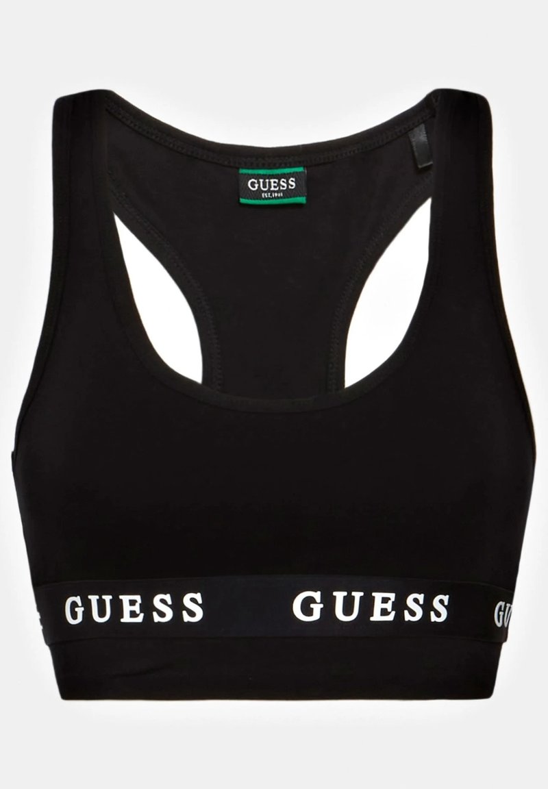 Brassière de sport noire dos nageur avec bande élastique portant le texte du logo GUESS en blanc et une étiquette de marque à l'intérieur du col.