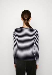 T-shirt med lång ärm och rundad halsringning i marinblå och vita horisontella ränder, tillverkad av lättviktig tyg, med avslappnad passform och sidoöppningar.