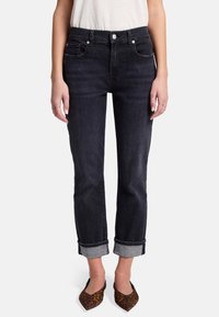 Jean en denim foncé avec une coupe droite, design minimaliste, ourlets roulés, cinq poches et un léger éclat. Associé à des ballerines à bout pointu.