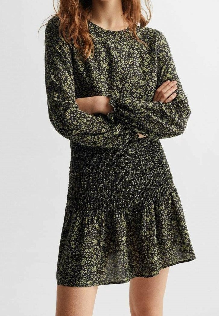 Black and green floral dress with long sleeves, smocked bodice, and flared skirt. Made of lightweight fabric with a soft texture.