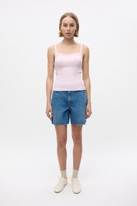 Hele roosa tank top, sinised teksashorts, millel on narmendav äär, kreemjad spordijalatsid ja beežid sokid. Lihtne, keha järgiv disain õhukeste rihmadega.