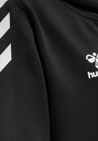 Černé sportovní tričko s hladkou texturou, na rameni s bílými diagonálními pruhy a bílým logem na hrudi.