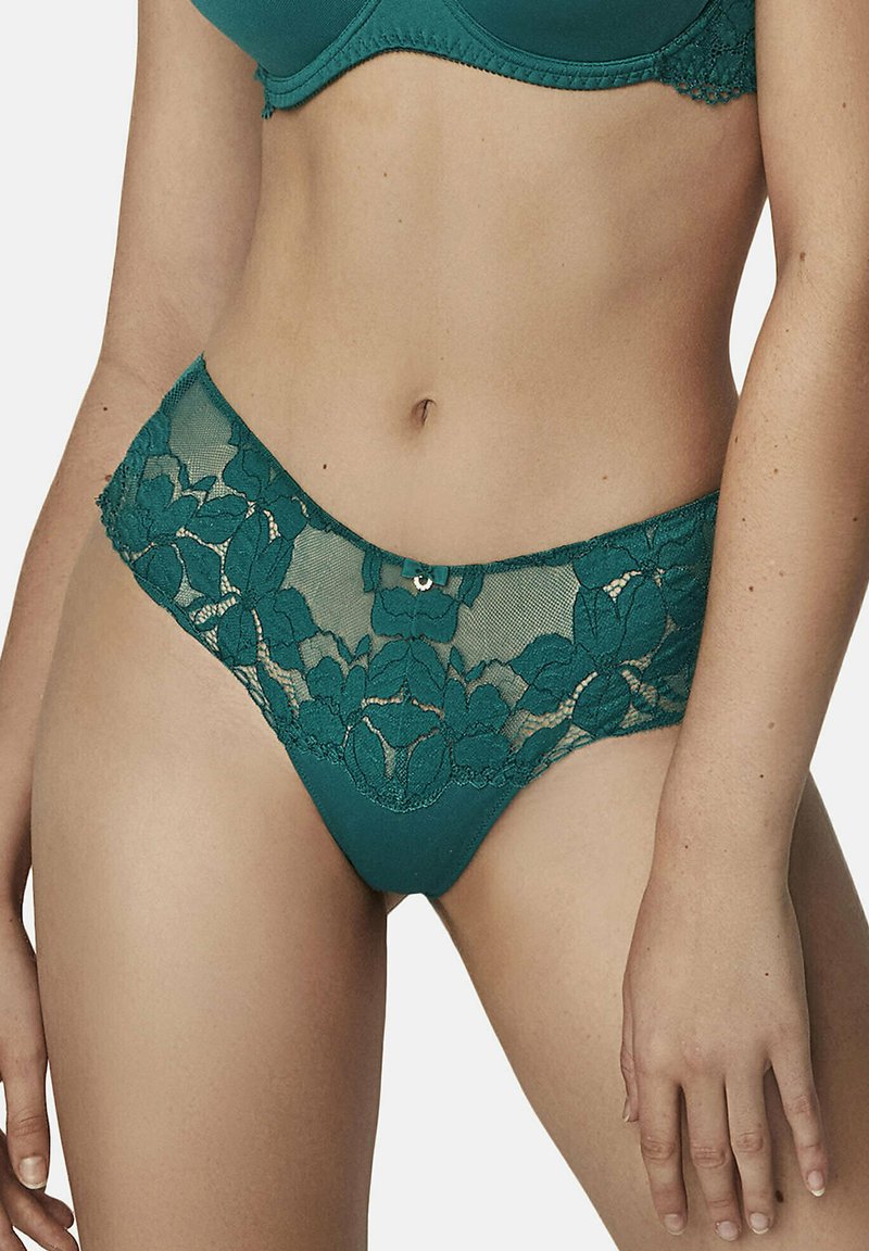 String en dentelle turquoise avec un motif floral, présentant une taille lisse et un petit bouton décoratif sur le devant. Texture en dentelle transparente.