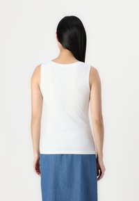 Weiße ärmellose Bluse mit Rundhalsausschnitt und glatter Textur, kombiniert mit einem Jeansrock, der eine schlichte und klare Gestaltung aufweist.