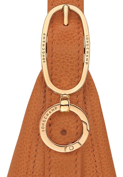 Lederner Schultergurt in Tan mit strukturierten Oberflächen. Goldfarbene Beschläge mit einer ovalen Schlaufe und einem runden Schlüsselring mit Gravur "LONGCHAMP".