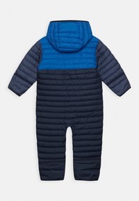 Padded kombinezon narciarski z niebieską górną częścią i granatowym dolnym segmentem. Posiada kaptur oraz długie rękawy o pikowanej fakturze.