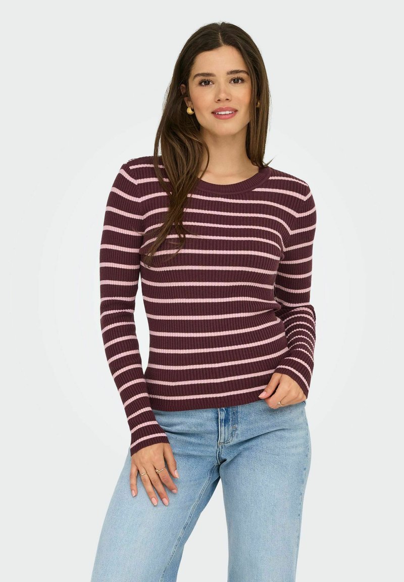 Pull à manches longues à côtes de couleur bordeaux profond avec des rayures horizontales roses. Encolure ras du cou, design ajusté, associé à un jean bleu clair.