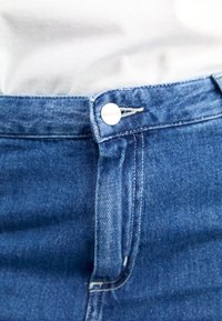 Blue denim jeans with a button closure, featuring a clean design, light distressing, and a single belt loop. The fabric has a smooth texture.