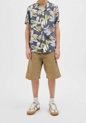 Kortærmet, knappet skjorte med blomstermønster i nuancer af blå, grøn og beige. Matcher med kaki-shorts og lyse sneakers.