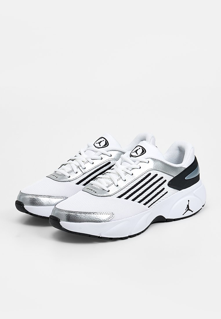 Par de zapatillas deportivas blancas y plateadas con detalles en negro y un logo negro en la suela y la lengüeta, mostradas sobre un fondo blanco.