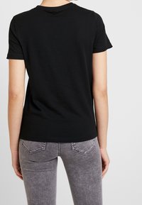 Svart bomull t-shirt med kort ärm, rund halsringning och figursydd form, tillsammans med grå strukturerade jeans med bakfickor.