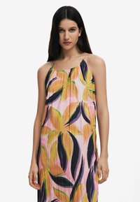 Abito maxi floreale con colori vivaci di rosa, giallo e verde, caratterizzato da una texture plissée, spalline sottili e una silhouette a forma di A.