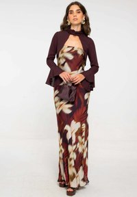 Largo vestido floral con un cuerpo en color burdeos y mangas acampanadas, con una falda en corte en ángulo en tonos de burdeos, crema y tonos terrenales. Acabado con un pequeño bolso.