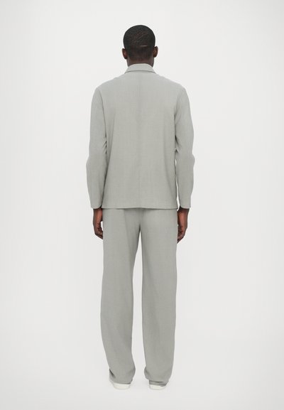 Γκρίζα σακάκι και παντελόνι από υφασμάτινη υφή, με καθαρή σιλουέτα και άνετη εφαρμογή, εμφανιζόμενα από το πίσω μέρος.
