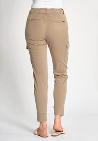 Beanie-Cargohose in Hellbraun mit elastischem Bund und seitlichen Cargotaschen. Weiche Textur mit schmal zulaufenden, eng anliegenden Beinen.