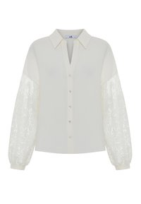 White blouse with a V-neck, button front, and puffed sleeves featuring floral lace details. Smooth fabric with a structured silhouette.