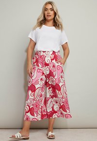 Blommiga, vida byxor med ett rosa och vitt mönster; tillverkade av lättviktsmaterial. Har ett elastiskt midjeband och sidofickor.