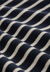 Tissu bleu marine avec des rayures blanches alternées, présentant un motif tricoté texturé. Les rayures ont une largeur égale, créant une apparence rythmée.