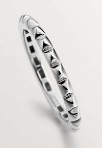 Pulsera de bangle de plata con una superficie lisa y acentos en forma de pirámide distribuidos a lo largo de la banda, creando un patrón geométrico.