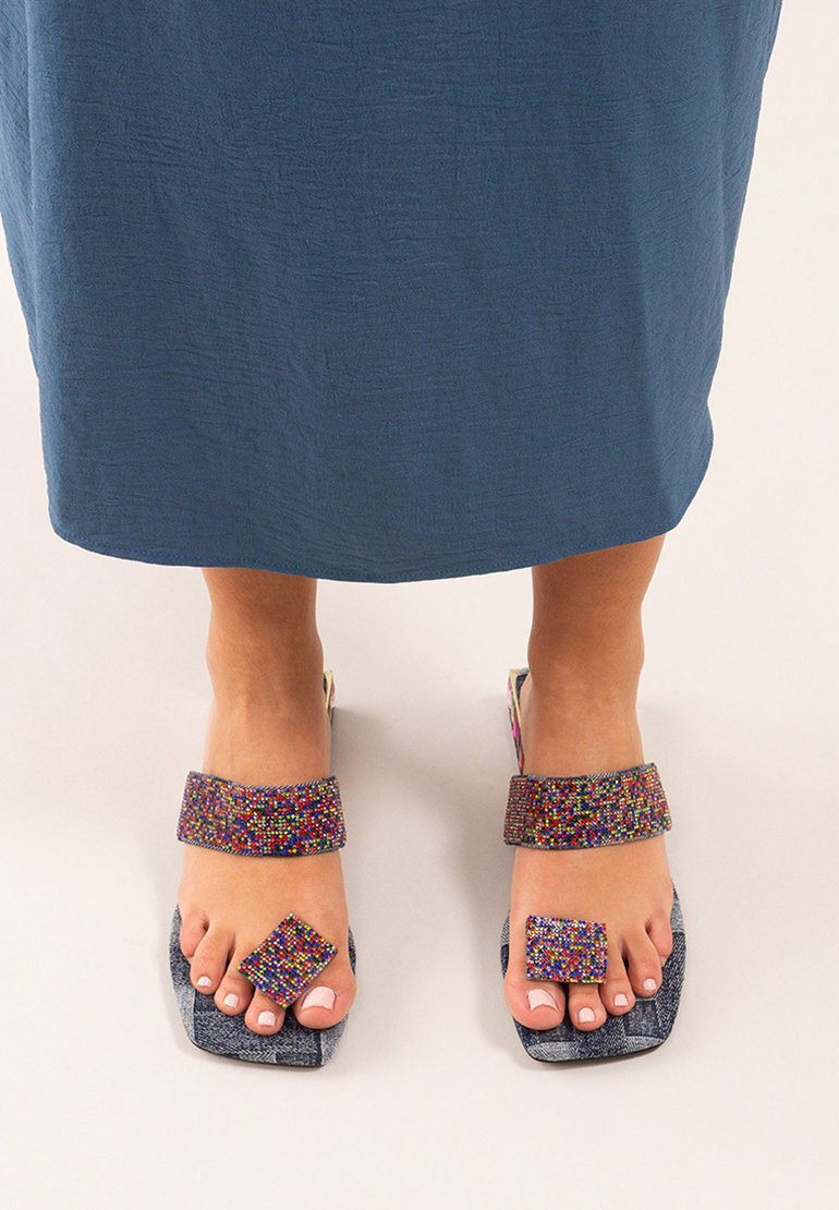 Sandalias con cuentas y acentos multicolores, tiras de tela y puntera cuadrada. La suela presenta una superficie azul texturizada.