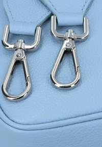 Borsa in pelle azzurro chiaro con dettagli in metallo argentato, dotata di due ganci a clip e superficie texturizzata. Bordo liscio e cuciture precise.