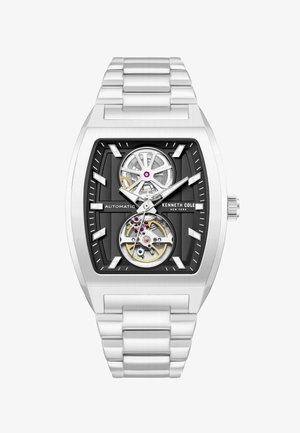 Reloj automático Kenneth Cole plateado con esfera negra, engranajes visibles, caja rectangular y pulsera de eslabones metálicos.